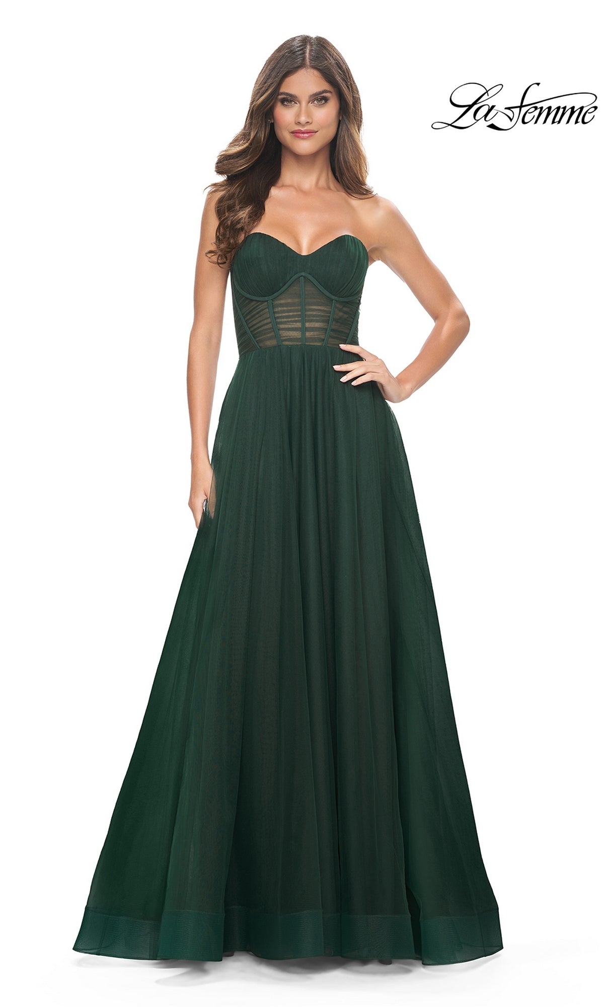 A woman models the La Femme Strapless Long A-Line Prom Dress 31971 in dark green, with a structured bodice and sheer panel details, against a plain white background.